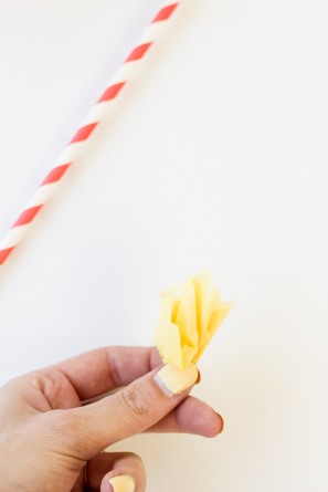 Someone holding yellow paper and a straw