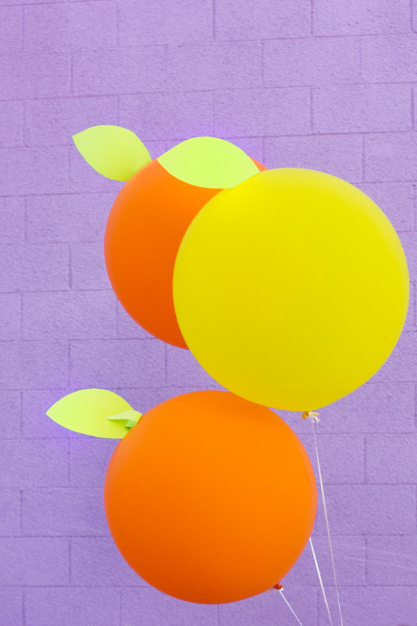 DIY Giant Citrus Balloons against a purple wall. 