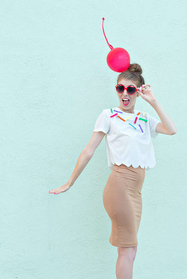 A person wearing an ice cream costume in front of a blue wall