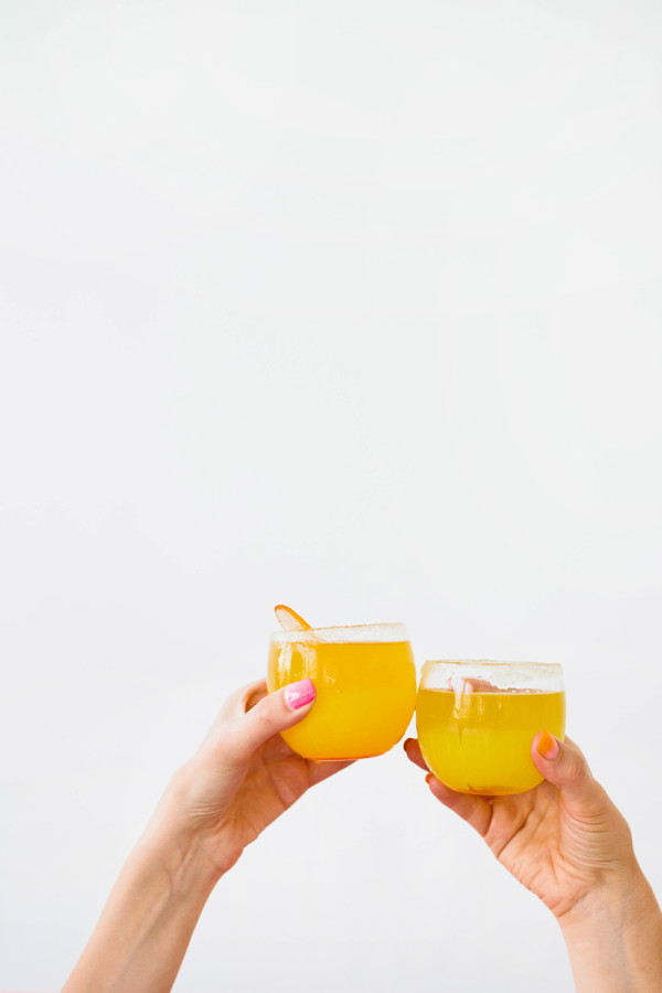 Two people holding two orange drinks