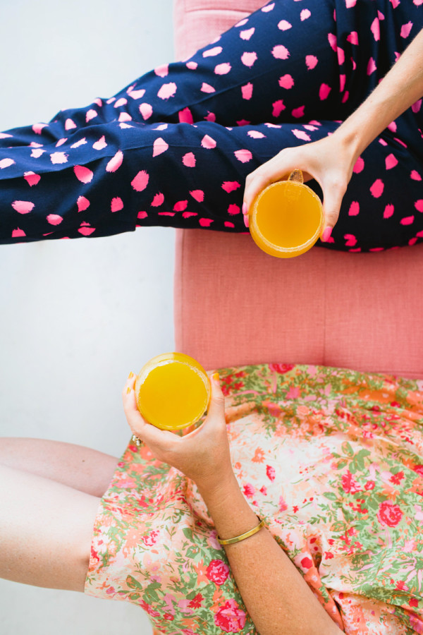 Two women holding orange drinks