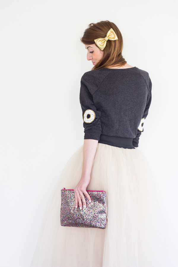 The back of someone wearing a sweater and skirt and holding a clutch