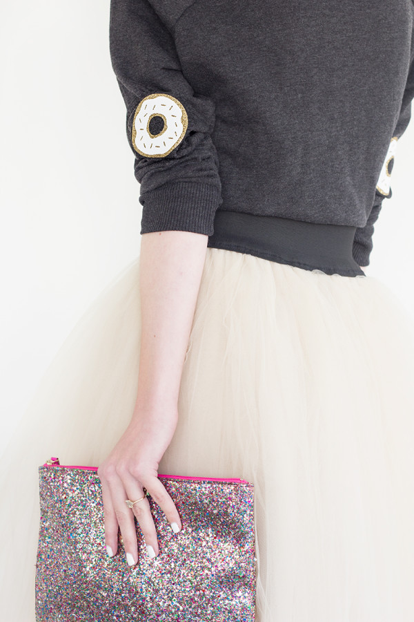 The back of someone wearing a sweater and skirt and holding a clutch