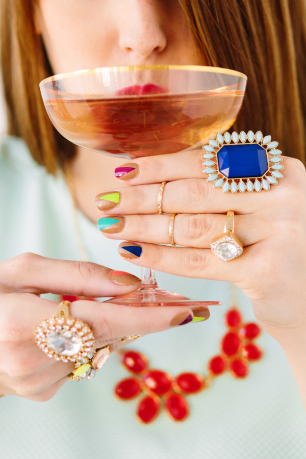 A women with rings and colorful nails holding a drink