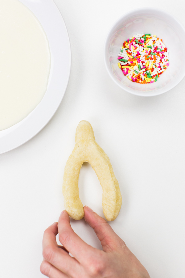 A wishbone donut and a bowl of sprinkles