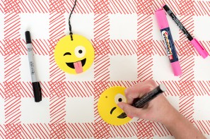 Someone drawing an emoji face on a ornament 