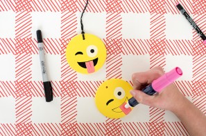 Someone drawing an emoji face on a ornament 