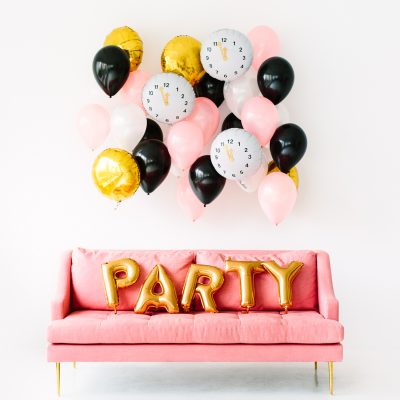 A pink couch with gold party balloons on it