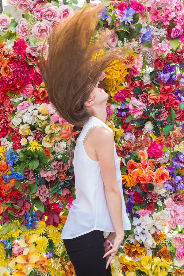 A woman in front of a bush of flowers