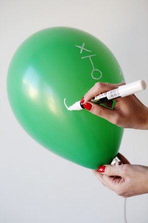 Someone drawing on a green balloon