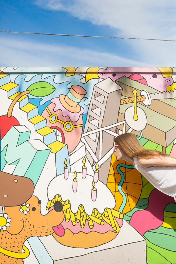 A woman in front of a colorful mural 