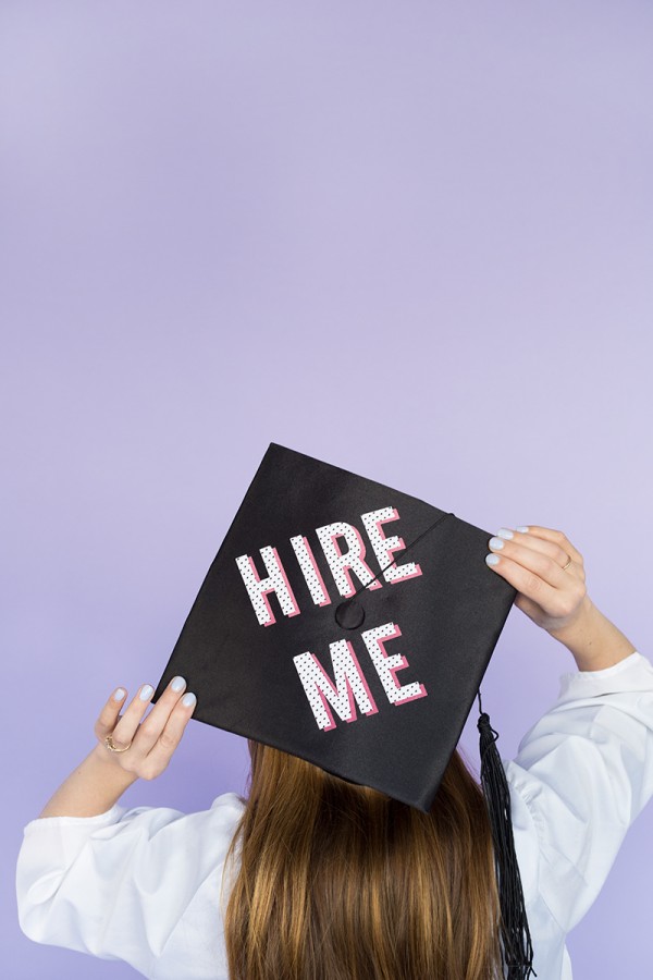 The back of a graduation cap that says \"hire me\"