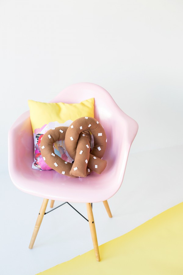 A pink chair with a pretzel pillow