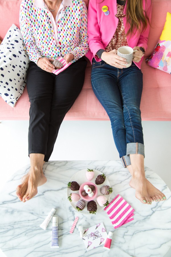 Two women sitting on a couch with their feet on a table