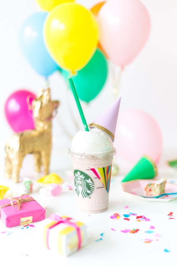 A close up of a starbucks drink with party decor in the background