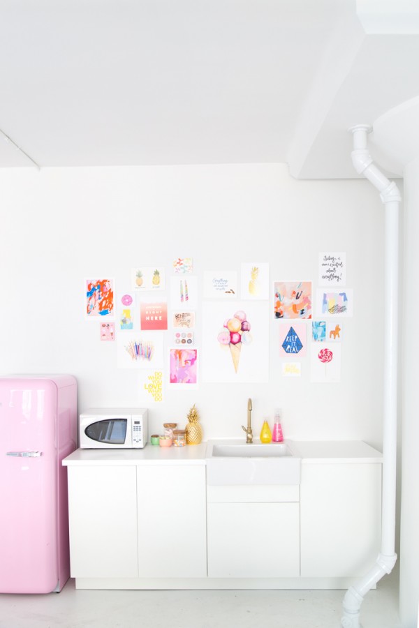 A kitchen with posters and a pink fridge