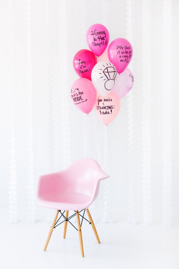 Pink balloons with words on it and a pink chair