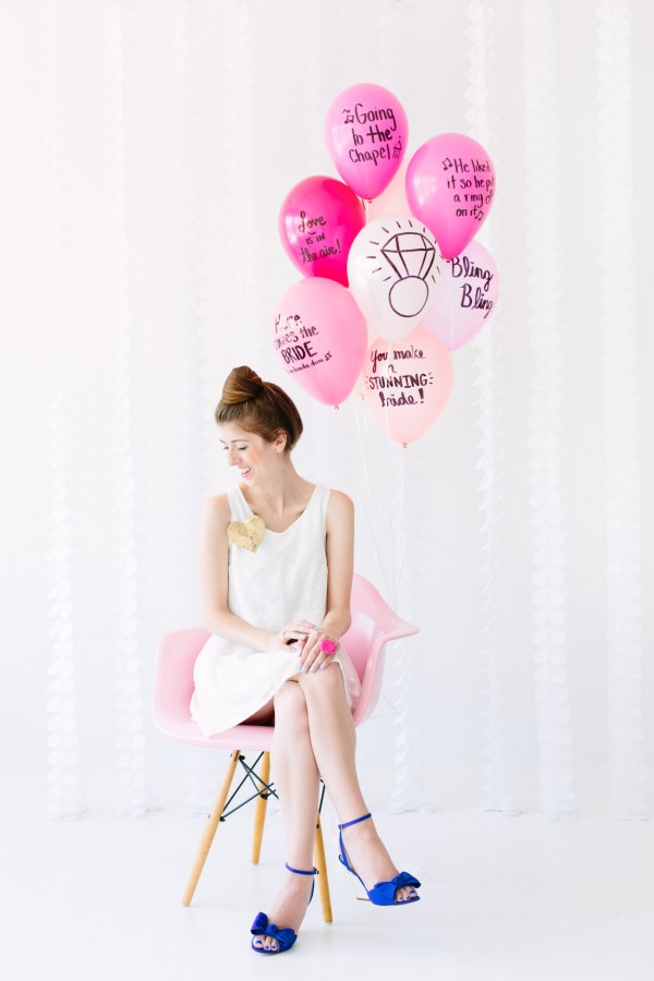 A woman sitting on a chair with pink balloons