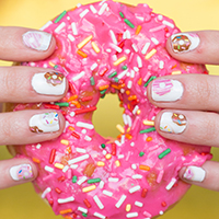 Someone holding a pink donut with sprinkles 