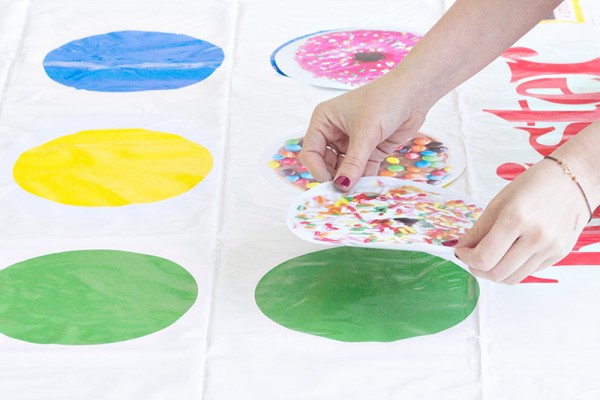 Someone putting donut stickers on a twister game