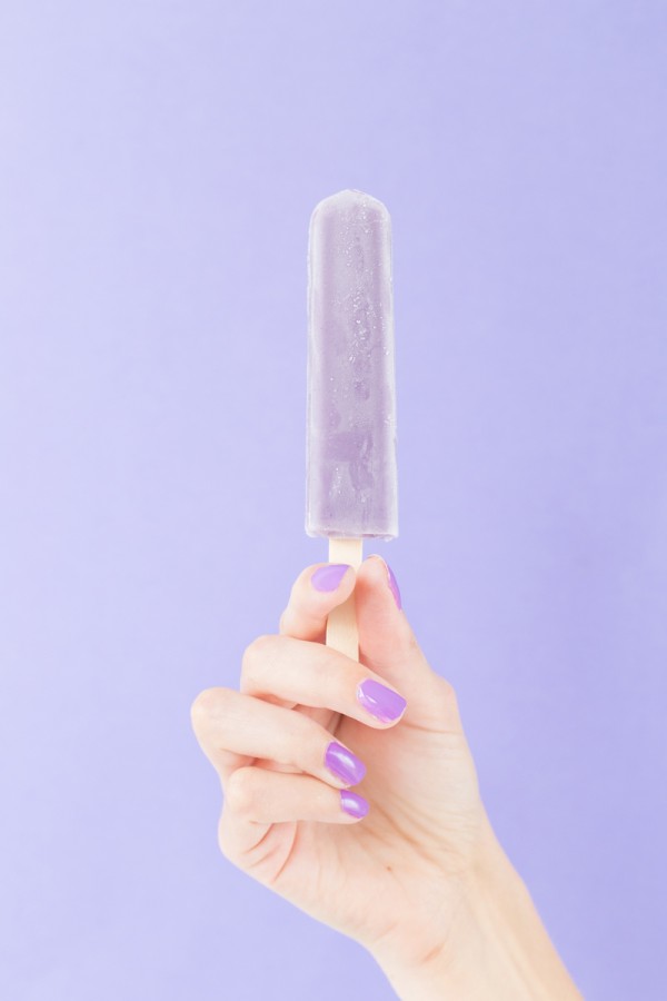 A woman holding a purple popsicle