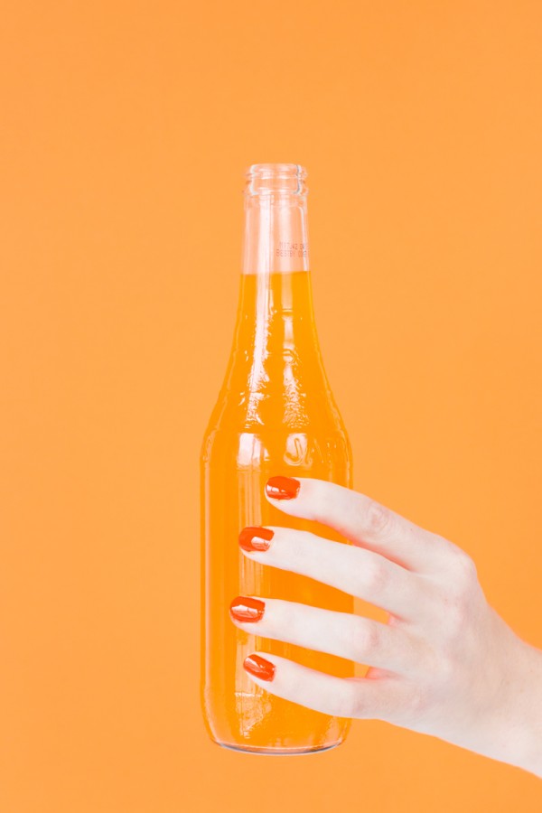 Someone holding a bottle with orange liquid