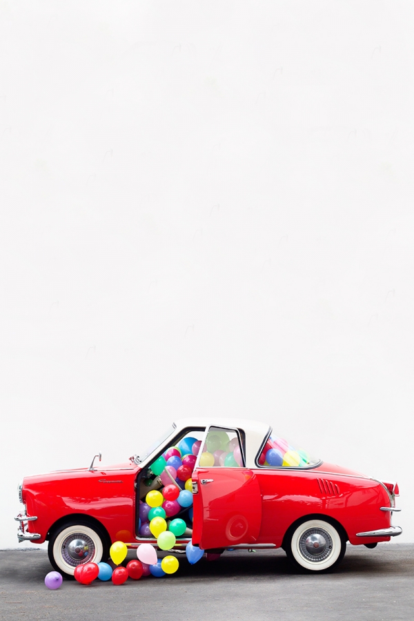 A red car with balloons in it