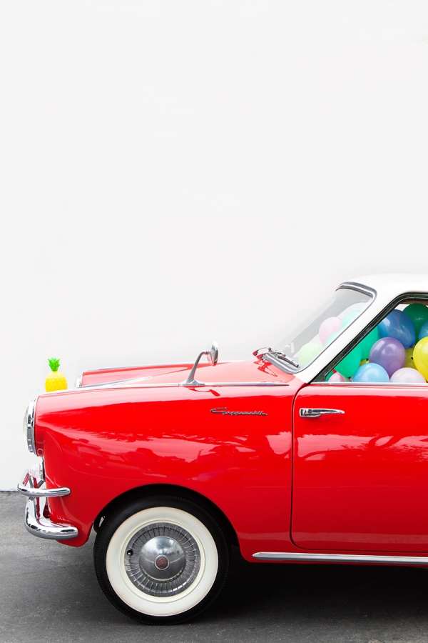 A red car with balloons inside of it