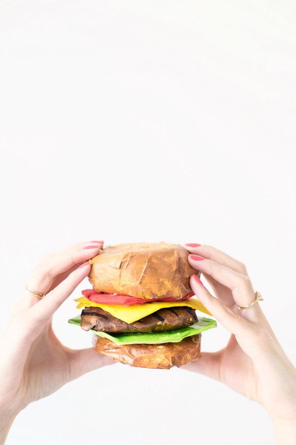 Someone holding a paper mache burger