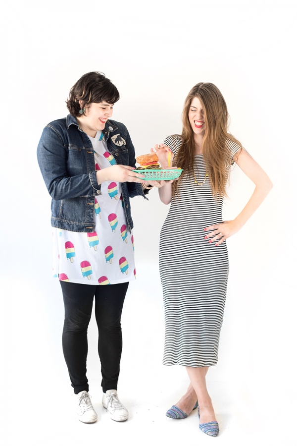 Two woman wearing dresses and holding a tray