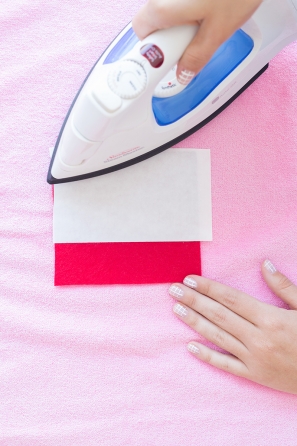 Someone ironing a red patch on pink fabric