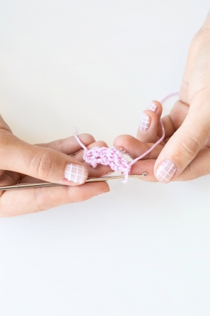 Someone holding a small pink knitted item