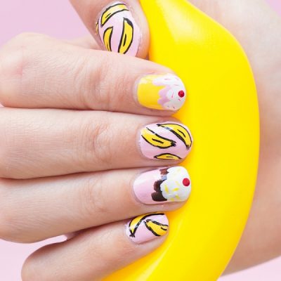 Someone holding a fake banana with banana split nails