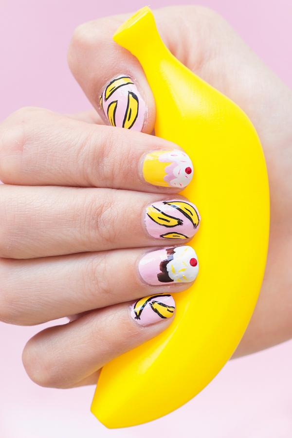 Someone holding a fake banana with banana split nails