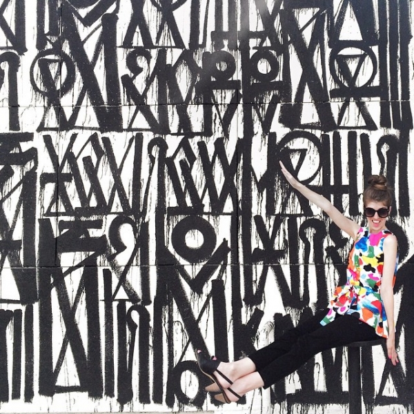A woman in front of a black and white mural