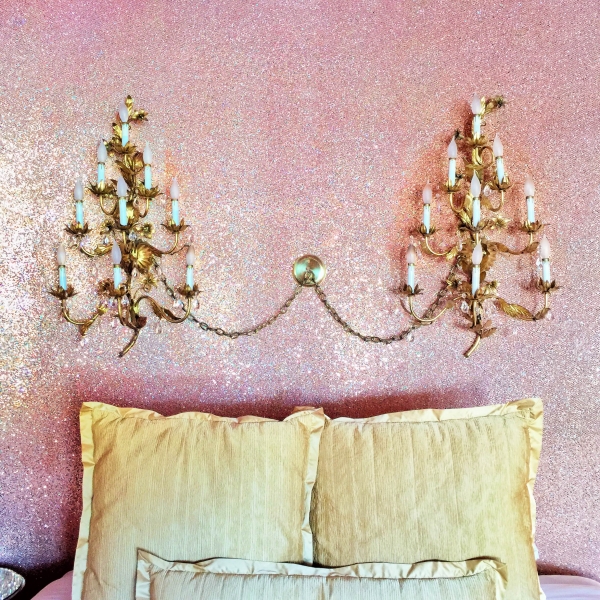 A bed with gold pillows and chandeliers 