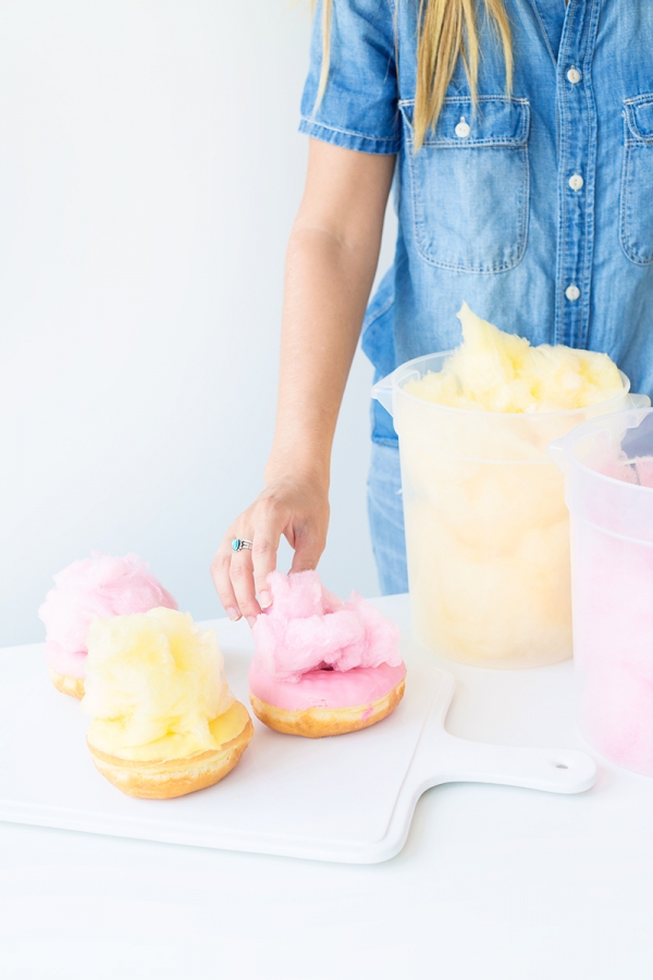 Someone putting cotton candy on a donut