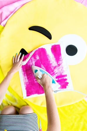 Someone ironing pink fabric on an emoji pillow