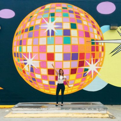 A woman standing in front of a disco ball mural