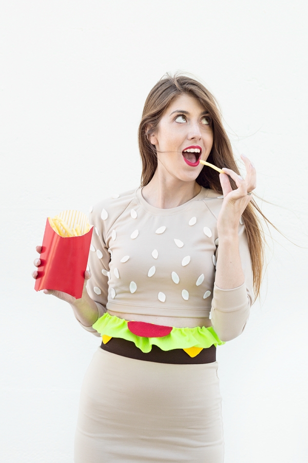 A woman in a burger costume, eating fries 