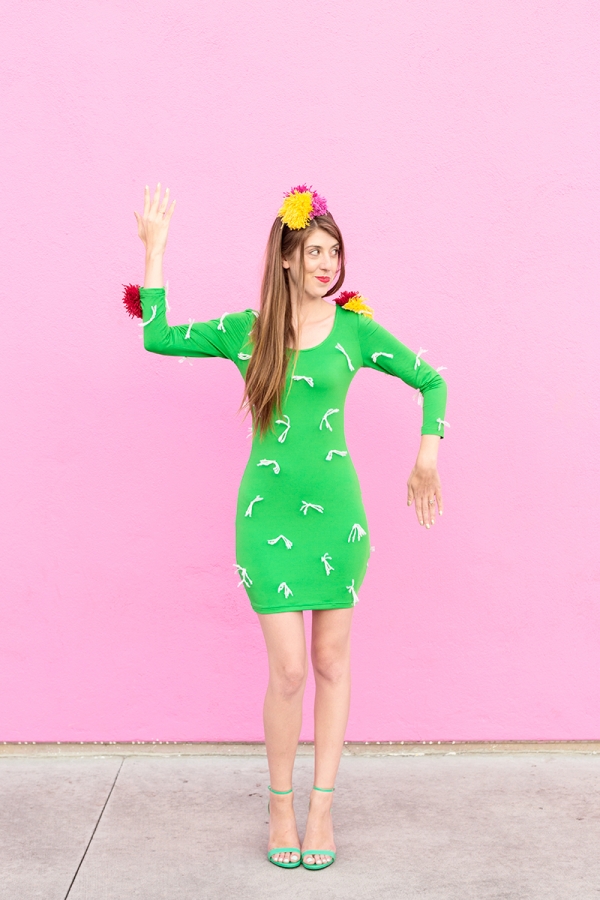 A woman wearing a cactus costume in front of a pink wall