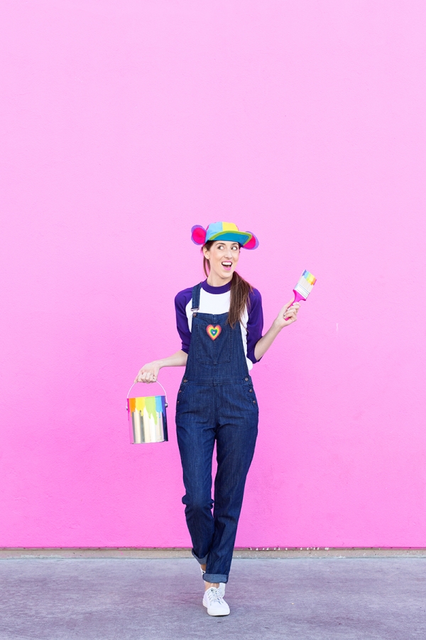 A woman wearing overalls and a rainbow hat