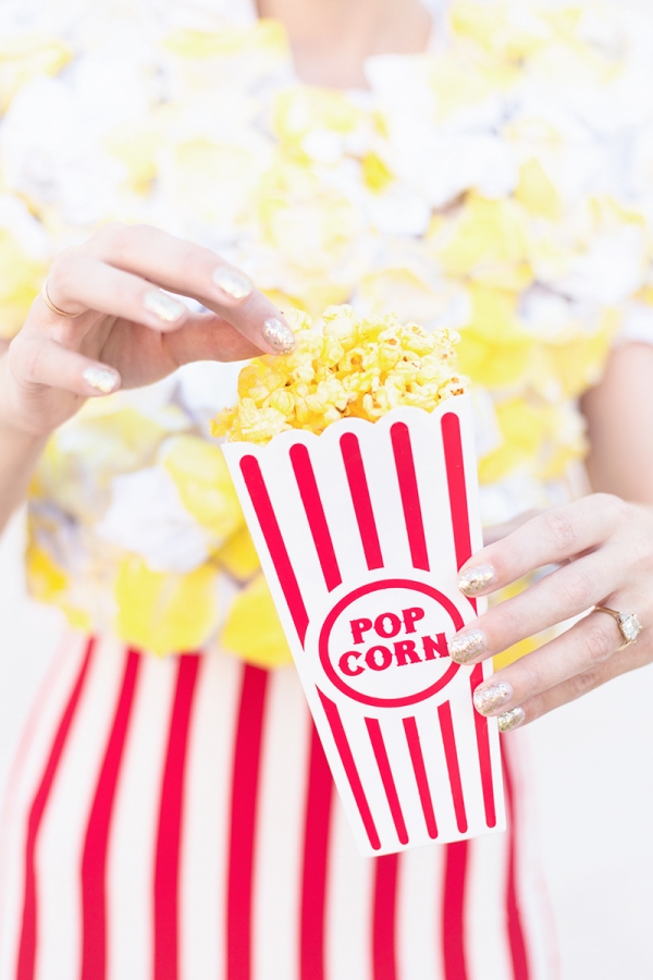 A woman wearing a popcorn costume and eating popcorn