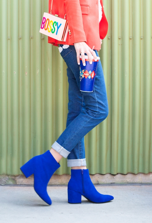 A close up of a woman in jeans and blue boots holding a drink