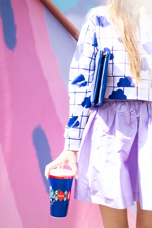 A close up of a woman wearing a white and blue shirt and purple skirt