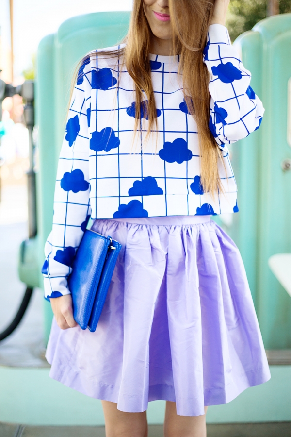 A close up of a woman wearing a blue shirt and purple skirt 