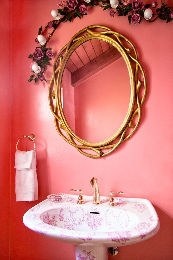 A pink bathroom with gold mirror