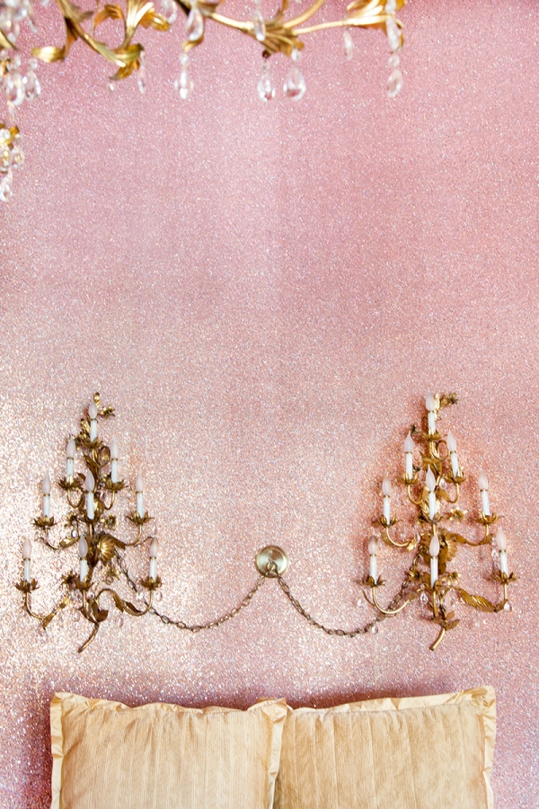 A close up a chandelier on a pink wall