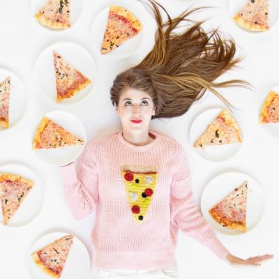 A woman lying down, surrounded by pizza