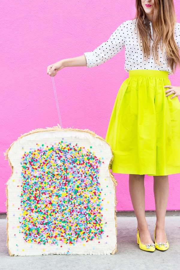 A woman in a yellow skirt and holding a fairy bread pinata 